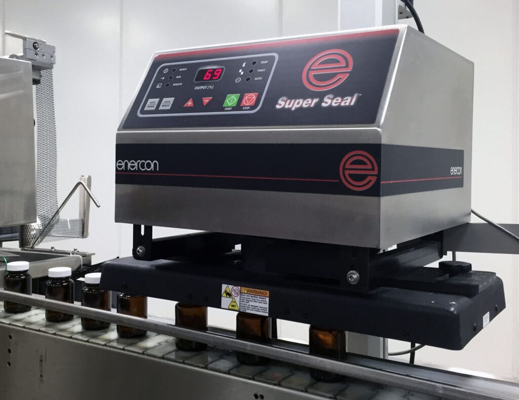 best-formulations-standardizes-on-enercon-cap-sealersr Capped containers are conveyed under the Enercon cap sealer.